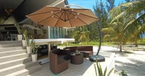 a patio with a table and an umbrella at Eagle Bay Retreat Borneo Beach Villas Beach Front in Kumbatang