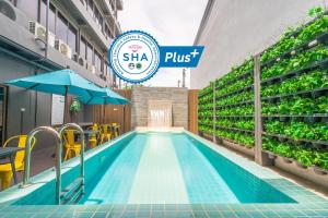 a swimming pool with chairs and umbrellas next to a building at Recenta Style Phuket Town in Phuket