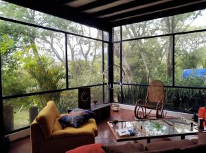 een woonkamer met grote ramen en een glazen tafel bij Casa del Aguacate Cumbaya - Tumbaco in Cumbayá