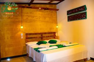 a bedroom with a bed with white sheets and green pillows at THURU VILLA in Katunayaka