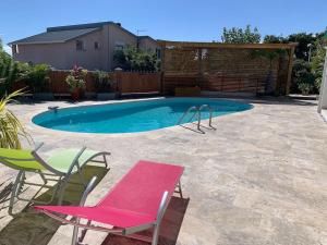 - une piscine avec 2 chaises et un banc rose dans l'établissement Malaury, splendide villa avec piscine chauffée, à Saint-Gilles les Bains