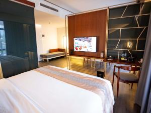 a bedroom with a bed and a desk and a tv at Rayz UMM Hotel Malang in Malang