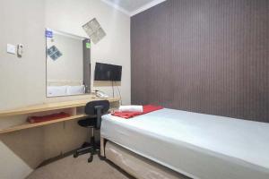 a bedroom with a bed and a mirror and a chair at Good Sleep Balikpapan Mitra RedDoorz in Balikpapan