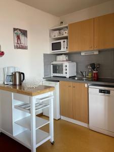 a kitchen with white appliances and a table in it at Le Corbier résidence Les Pistes in Le Corbier