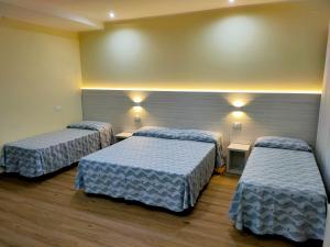 リミニにあるPark Hotelのベッド2台と壁に照明2つが備わる客室です。