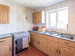 a kitchen with a stove and a sink and a window at The Bungalow in Cleobury Mortimer