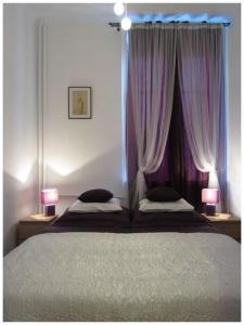 a bedroom with a bed with purple curtains and two lamps at Unique Warsaw Center Apartment in Warsaw