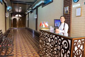 a woman standing at a counter in a hallway at Hotel Jasmina in Samarkand