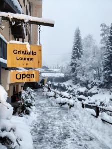 uma rua coberta de neve com um sinal que diz Christian lelelelele em Hotel Cristallo em Alagna Valsesia