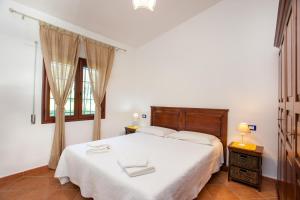 a bedroom with a large white bed and a window at Casa Osala in Orosei