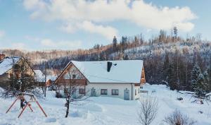 a house with snow on the roof of it at Domek pod Szarowym lasem in Wisła