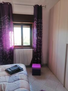 Schlafzimmer mit einem Bett und einem Fenster mit lila Vorhängen in der Unterkunft Villetta immersa nel verde in Piazza Armerina