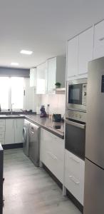 a kitchen with white cabinets and stainless steel appliances at NAUTILUS in Torrevieja