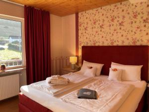 a bedroom with a large bed with a book on it at NaturPurHotel Maarblick in Meerfeld