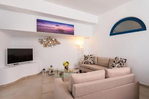 a living room with a couch and a tv at Villa Waves in Monolithos