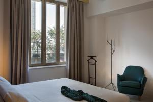 Pokój hotelowy z łóżkiem i zielonym krzesłem w obiekcie Corso Novara 5 Design Apartments w mieście Neapol