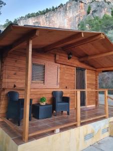una terraza de madera con 2 sillas y una mesa en Cabanas El Nogueral, en Gontar