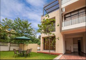 Un patio con una mesa y sillas y una sombrilla. en StayVista's Greenwoods Villa 7 - City-Center Villa with Private Pool, Terrace, Lift & Ping-Pong Table, en Lonavala