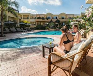 dos mujeres sentadas en sillas junto a una piscina en Helios Apartments, en Kato Daratso