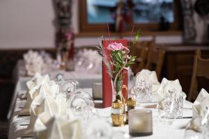einen Tisch mit einer Vase mit einer Blume darin in der Unterkunft Hotel Post Krimml in Krimml