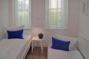 Pokój z 2 łóżkami i stołem z niebieskimi poduszkami w obiekcie Villa Poseidon - WE 5 in Strandnähe und zentrumsnah w mieście Binz