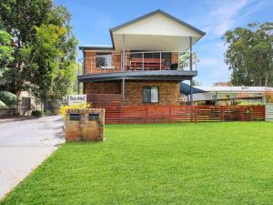 a brick house with a balcony on top of a yard at Sea Side on Russell in Hawks Nest