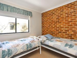 two beds in a room with a brick wall at Sea Side on Russell in Hawks Nest