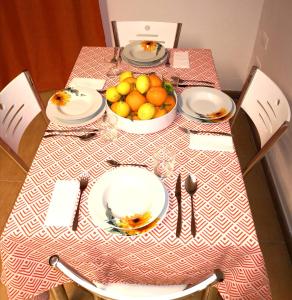 un tavolo con piatti e un cesto di frutta di CASA QUIDERA LOCAZIONE TURISTICA / AFFITTI BREVI a Castelvetrano Selinunte