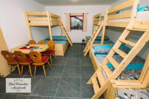 a room with bunk beds and a table and chairs at Hostel Bled Paradise Slovenia in Bled-Rečica