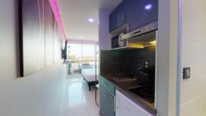 a kitchen with blue cabinets and a room with a bed at Village Naturiste Cap d'Agde, Studio Luxe Port Nature 7 in Cap d'Agde