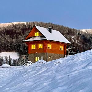una gran casa de madera en la nieve con nieve en Roubenka pod Lysou - Malenovice, en Malenovice