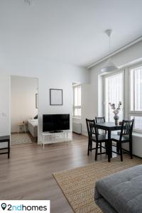a white living room with a table and chairs at 2ndhomes Tampere "Areena" Apartment in Tampere