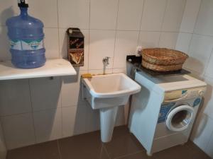 a bathroom with a sink and a washing machine at Apartamento Frente para o Mar - Varandão com Blindex - Vista Total para o Mar - 1 Suite e mais 2 Quartos-Ar Condicionado - 2 Vagas - BEIRA MAR - 70 metros da Praia ,TVS SMART GERAL -WI-FI -DISNEY PLUS-OUTROS- PORTARIA 24 HORAS-KIT PRAIA 4 PESSOAS in Guarapari +130 photos