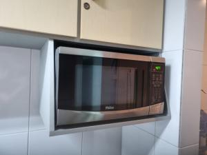a microwave oven hanging on a wall in a kitchen at Apartamento Frente para o Mar - Varandão com Blindex - Vista Total para o Mar - 1 Suite e mais 2 Quartos-Ar Condicionado - 2 Vagas - BEIRA MAR - 70 metros da Praia ,TVS SMART GERAL -WI-FI -DISNEY PLUS-OUTROS- PORTARIA 24 HORAS-KIT PRAIA 4 PESSOAS in Guarapari