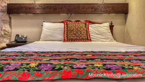 a bed with a colorful quilt on it with a phone at Jerusalem Hotel in Jerusalem