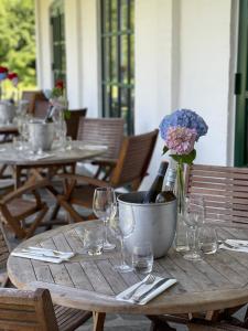 una mesa de madera con copas de vino y un jarrón de flores en Hotel Nygaard Læsø en Byrum