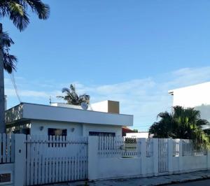 una cerca blanca frente a una casa blanca en Residêncial Casa da Vila apto 1, en Imbituba