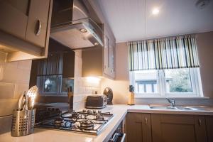 a kitchen with a stove top oven next to a sink at Warrenwood Country Park in Polegate