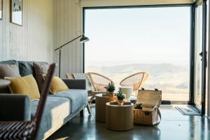 ein Wohnzimmer mit Sofa, Sesseln und einem großen Fenster in der Unterkunft Cabañas Huma 2 in Vegadeo