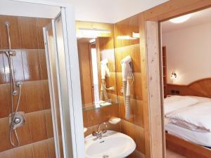 a bathroom with a sink and a shower and a bed at Albergo Arnica in Canazei +122 photos