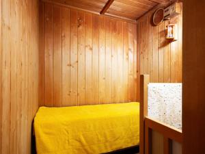 um quarto com uma cama amarela numa parede de madeira em A-GATE HOTEL 旭川 -Asahikawa- em Asahikawa