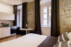 a bedroom with a bed and a table and a kitchen at Romantic studio in the heart of Trieste in Trieste