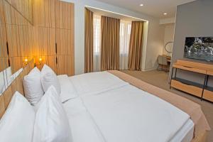 a bedroom with a large white bed and a television at Cartez Hotel in Yerevan