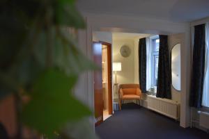 un corridoio con una sedia arancione e una finestra di Hotel Atlanta a Valkenburg