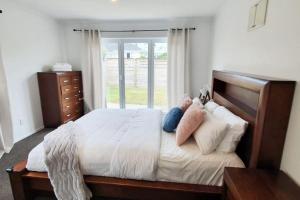 ein Schlafzimmer mit einem großen Bett mit weißer Bettwäsche und Kissen in der Unterkunft Cheerful 3BR Home With Free WiFi & Netflix in Auckland