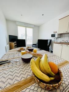un tazón de plátanos y naranjas sobre una mesa en Residence Louis Place du Marche en Bains-les-Bains