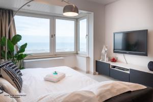 a bedroom with a large window and a television at Frontaal zeezicht "Martinique" in Ostend