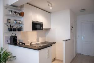 a kitchen with white cabinets and a sink at Frontaal zeezicht "Martinique" in Ostend