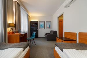 una habitación de hotel con 2 camas y una silla en Hotel Edison, en Przeźmierowo
