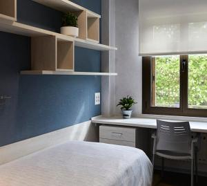 a bedroom with a bed and a desk and a window at Albergue Residencia Larraona in Pamplona